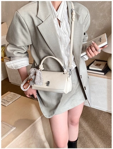 Detail of off-white lychee pattern leather handbag with silver lock and plush bunny charm