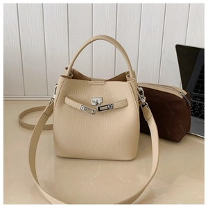 Detailed macro view of beige lychee leather texture and silver buckle on a bucket bag