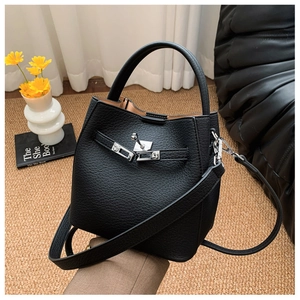 Detail of black lychee grain leather bucket bag with silver metal twist lock and strap