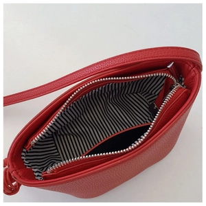 Top view of red textured leather crossbody bag with striped lining and inner zipper pocket