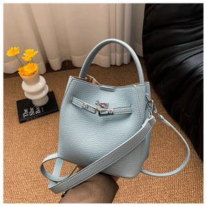 Detail of light blue pebbled leather bucket bag with silver twist lock and woven mat background