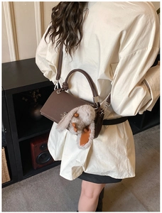 Back view of a woman wearing a dark brown crossbody square bag with a cute plush bunny charm