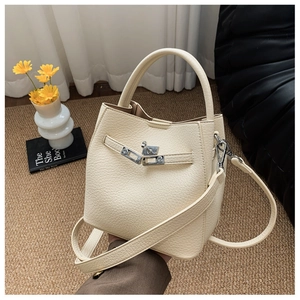 Detail of cream white pebbled leather bucket bag with silver metal swivel lock hardware