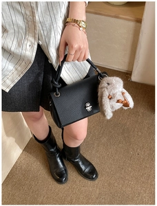 Close-up of black litchi grain leather handbag with silver twist lock and bunny charm