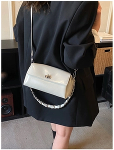 Detail of light grey glossy leather shoulder bag with silver turn-lock and chain strap