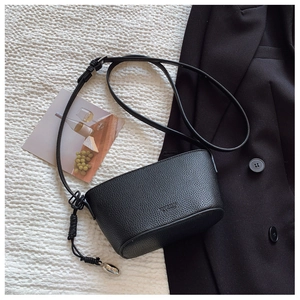 Detail of black lychee grain leather bucket bag with silver oval charm and knot decor