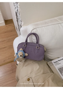 Detail der lila Boston Tasche mit Leder in Litschi-Struktur und süßem Bärenanhänger