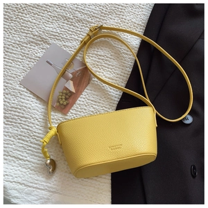 Detail of yellow lychee pattern bucket bag with silver heart pendant on white fabric