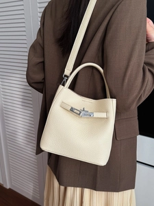 Beige lychee pattern leather bucket bag worn by model with adjustable shoulder strap