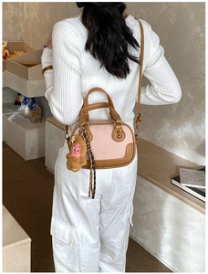 Detail showing the pink and brown bowling bag with cartoon charm in a lifestyle setting