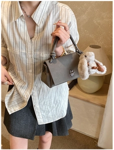 Detailed view of grey tote bag with knot handle and plush rabbit charm on side
