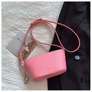 Detailed overhead view of a pink faux leather crossbody bag with lychee texture finish