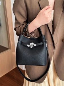 Elegant black pebble leather bucket bag with silver clasp carried by a model
