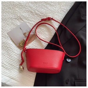 Detail of red lychee grain leather bucket bag with silver heart pendant and shoulder strap