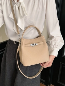 Elegant beige bucket bag with lychee grain leather finish and metal twist lock