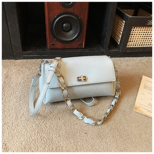 Close-up of light blue faux leather handbag with silver rotary lock and metal chain strap