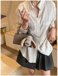 Detail of gray matte leather crossbody bag with cute plush rabbit pendant charm