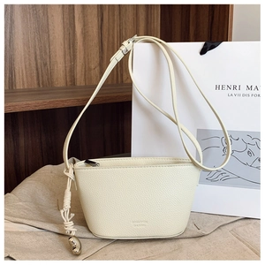 Detail view of cream lychee texture leather bag with metallic gold ball pendant