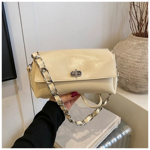 Close-up of off-white leather shoulder bag with silver chunky chain and metal twist lock
