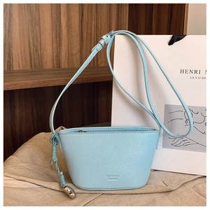 Detail shot of light blue litchi pattern leather bag with silver ball charm and knot strap