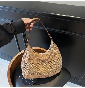 Detail view of woven straw shoulder bag featuring mesh knit patterns and leather handles