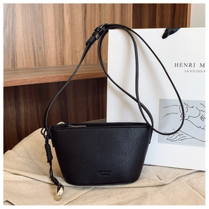 Close-up of black litchi grain leather bag with woven knot detail and metal zipper hardware