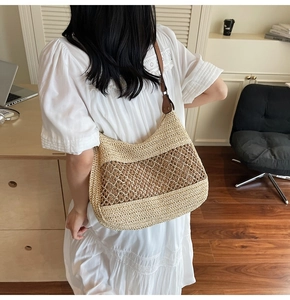 Model wearing straw woven shoulder bag with hollow patterns and brown leather strap