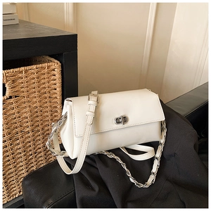 Detail of a white crossbody bag with silver twist lock and chain strap on a black blazer