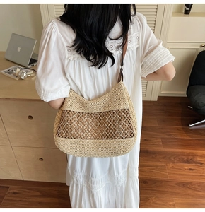 Detailed macro view of handcrafted woven straw shoulder bag with dark leather strap