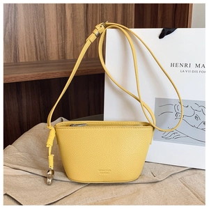Detail view of yellow lychee grain leather mini crossbody bag with heart pendant charm