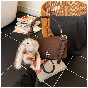 Detail of dark brown lychee leather handbag with silver twist lock and plush rabbit charm