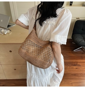 Detail of a large brown straw tote bag featuring stylish hollow mesh weaving and leather strap