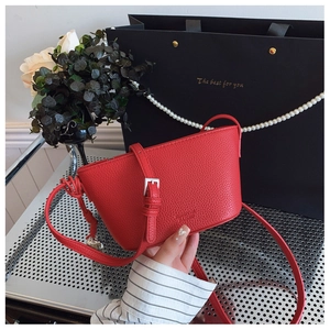 Detail of red lychee pattern bucket bag with silver buckle and brand logo