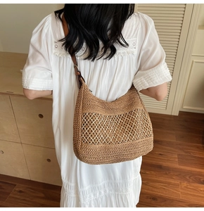 Detail of hand-woven brown straw hobo bag featuring hollow mesh and adjustable leather strap
