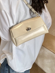 Elegant cream patent leather crossbody bag with silver twist lock and chain strap on model