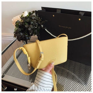 Detail showing bright yellow lychee textured bucket bag with metallic side buckle