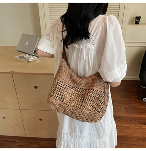 Detail of a brown woven straw shoulder bag with leather strap in a lifestyle setting