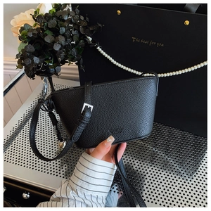 Detail of black lychee grain leather crossbody bag with letter embossing and metal buckle