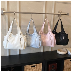 Détail de quatre sacs cabas en blanc cassé, bleu, rose et noir avec des poches latérales