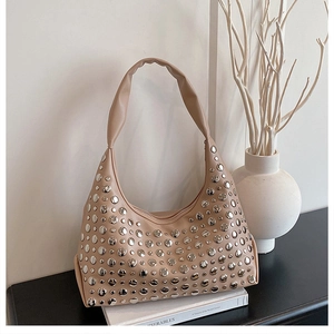 Nahaufnahme der beigen Ledertasche mit silbernen Nieten auf minimalistischem Dekor