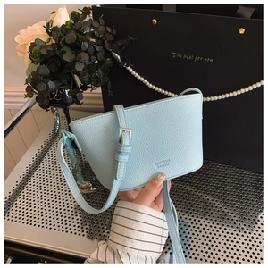 Detail of light blue crossbody bag with lychee grain texture and heart metal pendant