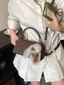 Elegant dark brown leather crossbody bag with a cute plush bunny charm and silver hardware