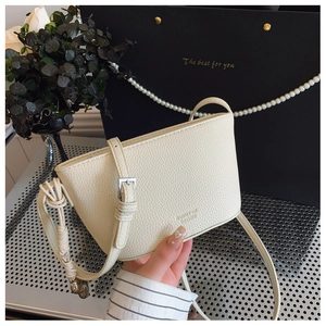 Detailed close-up of beige lychee texture leather shoulder bag with knot strap detail