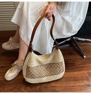 Detail of bohemian straw shoulder bag with mesh weave and brown leather strap