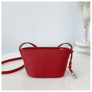 Close-up of red lychee pattern leather shoulder bag with knot detail and silver charm