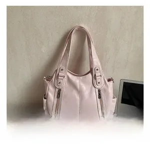 Détail du sac cabas rose montrant la texture du cuir et la poche latérale sur table