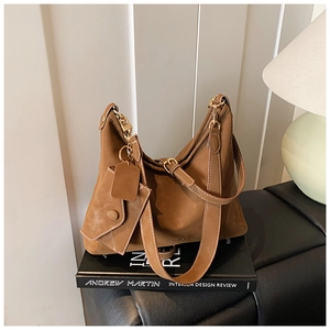 Detailed close-up of brown suede hobo bag featuring white contrast stitching and gold buckle