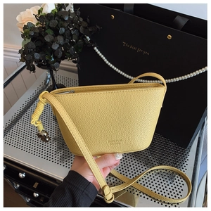 Macro shot of yellow lychee pattern leather crossbody bag with brand logo embossing