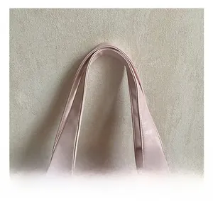 Détail de sac cabas rose clair avec poignées en cuir souple et rivets argentés