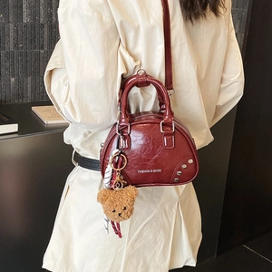 Chic burgundy leather bowling bag with a cute bear charm and gold stud details